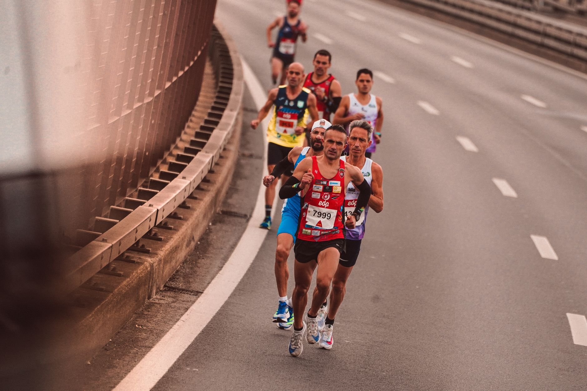 A group of male athletes competing in a city marathon, featuring diverse runners and dynamic movement